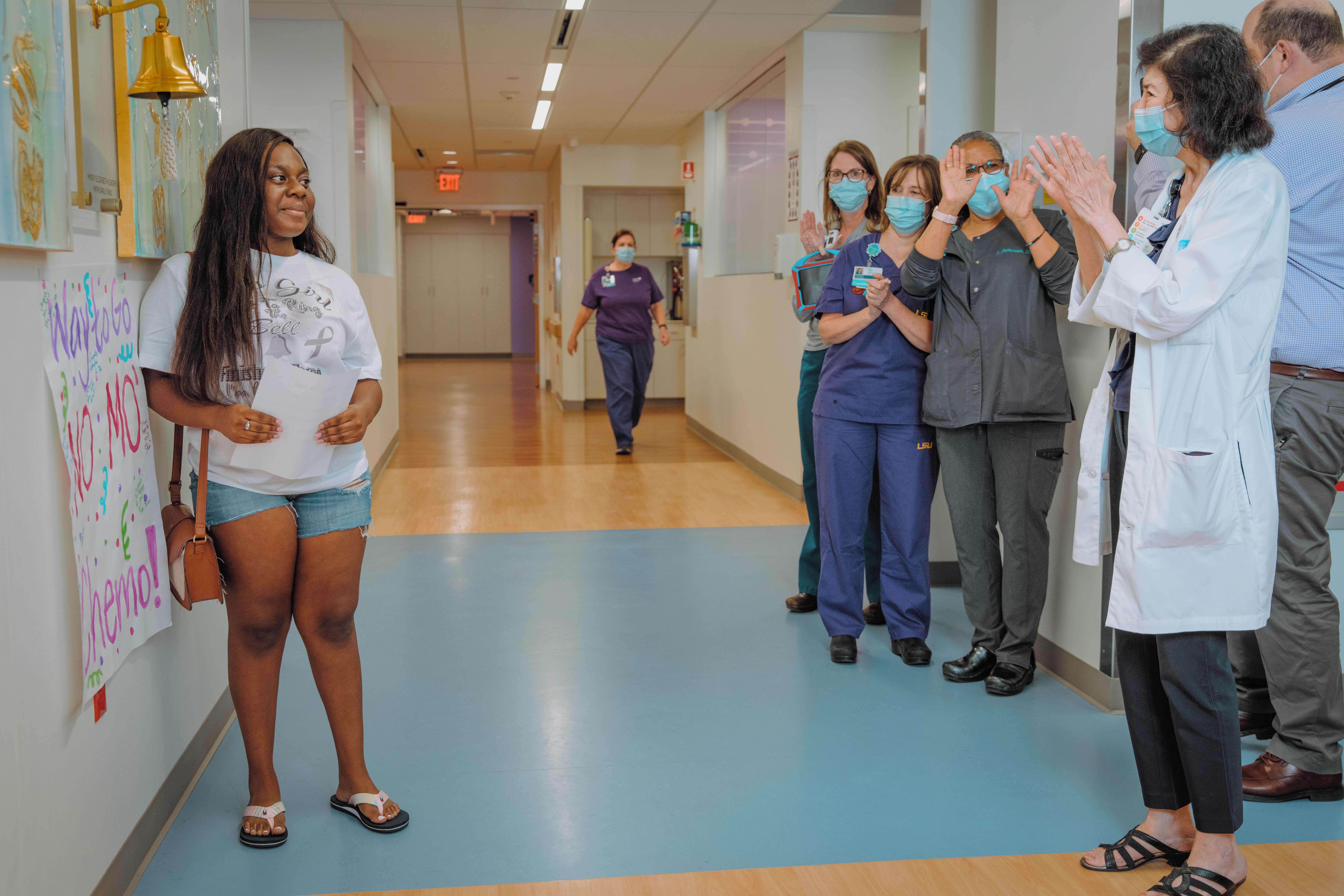 Young woman standing in hallway while providers clap for her